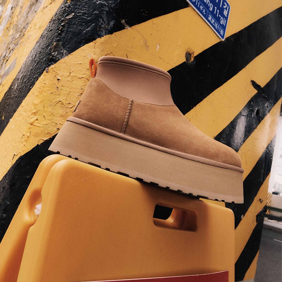 A chestnut-colored UGG Classic Mini Dipper atop a signpost easel.